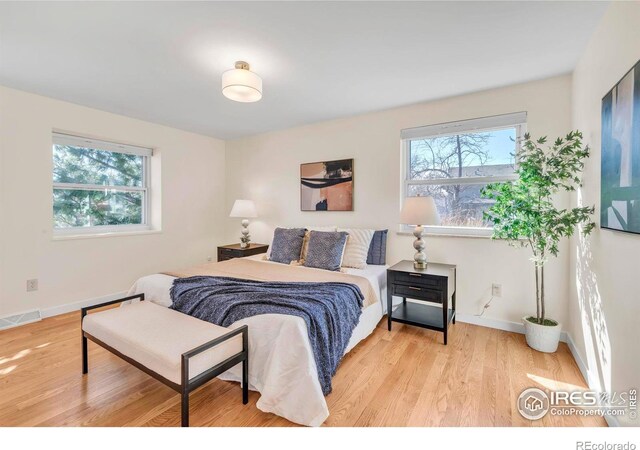 bedroom with visible vents, multiple windows, baseboards, and wood finished floors