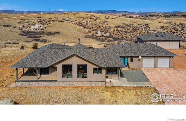 view of front of home with a patio area, a garage, driveway, and stucco siding