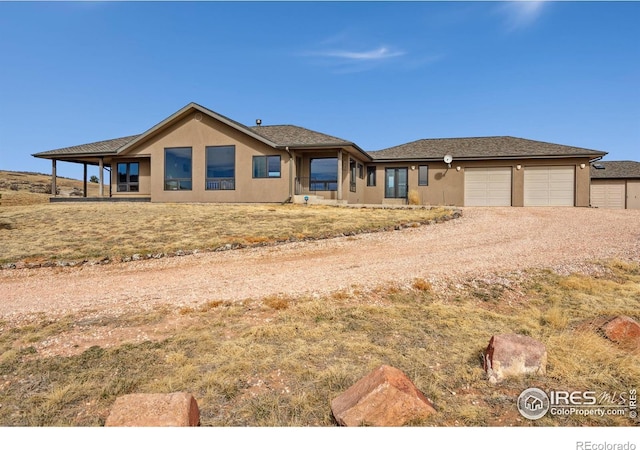 view of front of property featuring stucco siding, an attached garage, and dirt driveway