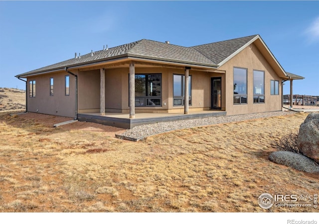 back of property featuring stucco siding, roof with shingles, and a patio area