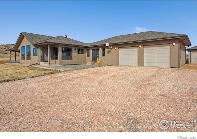 ranch-style house featuring an attached garage, driveway, and stucco siding