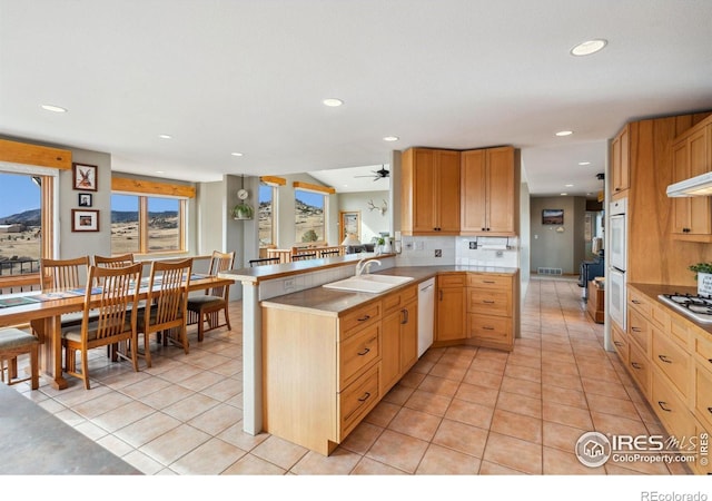 kitchen with a sink, tasteful backsplash, a peninsula, and light tile patterned flooring