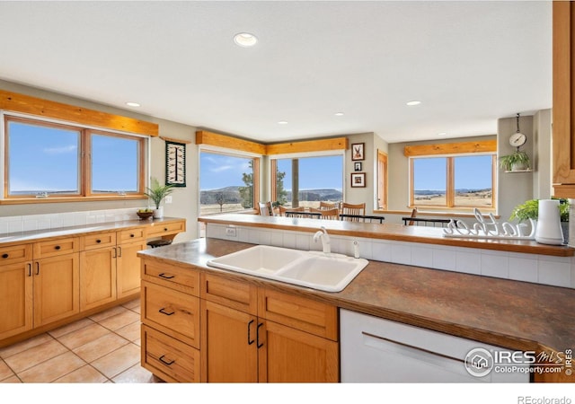 kitchen featuring light tile patterned floors, recessed lighting, dark countertops, and a sink