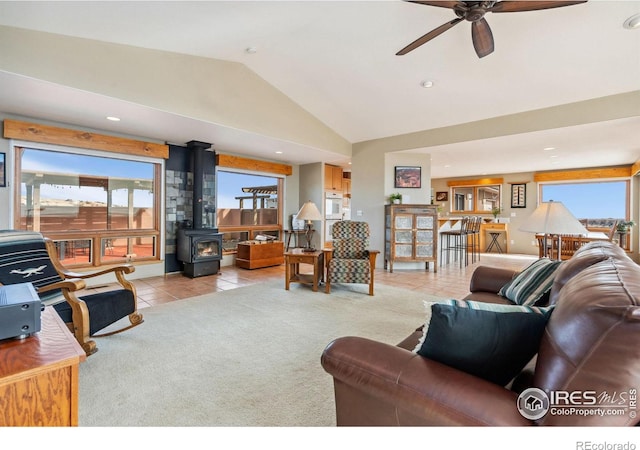 tiled living room with a wood stove, lofted ceiling, a healthy amount of sunlight, and carpet flooring