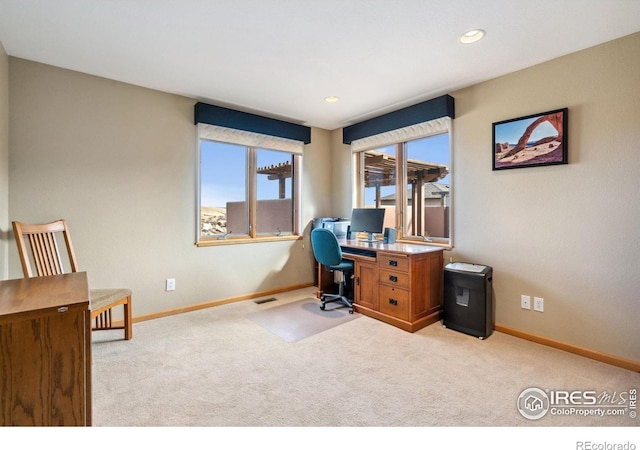 office space with light carpet, visible vents, and baseboards