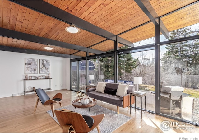 living area with beam ceiling, wood finished floors, wooden ceiling, a wall of windows, and baseboards