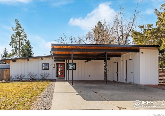 view of front of property with a front yard, a carport, board and batten siding, and driveway