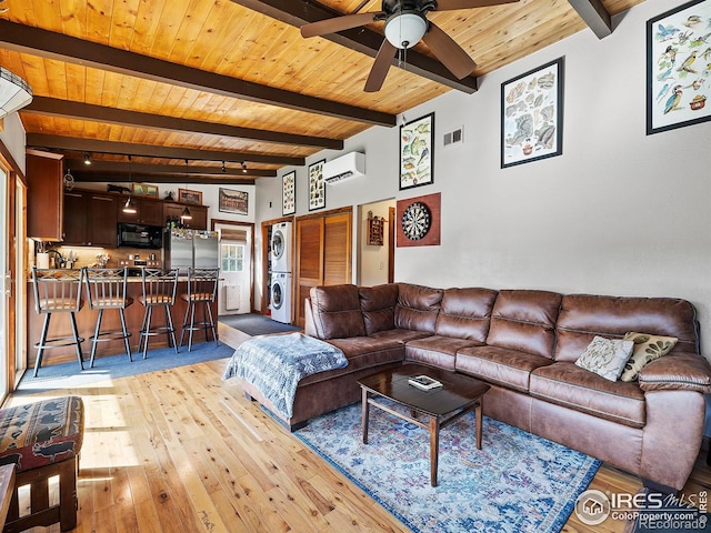 living area featuring visible vents, beamed ceiling, a wall unit AC, stacked washer / drying machine, and wood ceiling