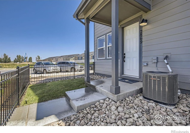 entrance to property with a porch, central AC unit, fence, and a residential view