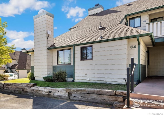 view of property exterior with a chimney and a shingled roof