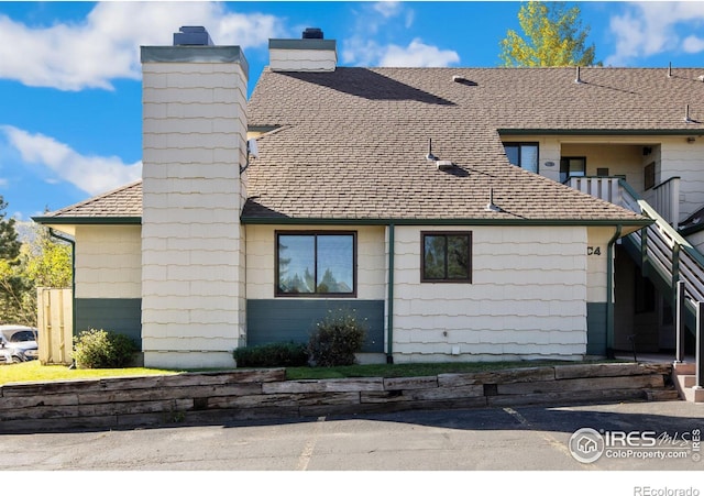 exterior space with roof with shingles and a chimney