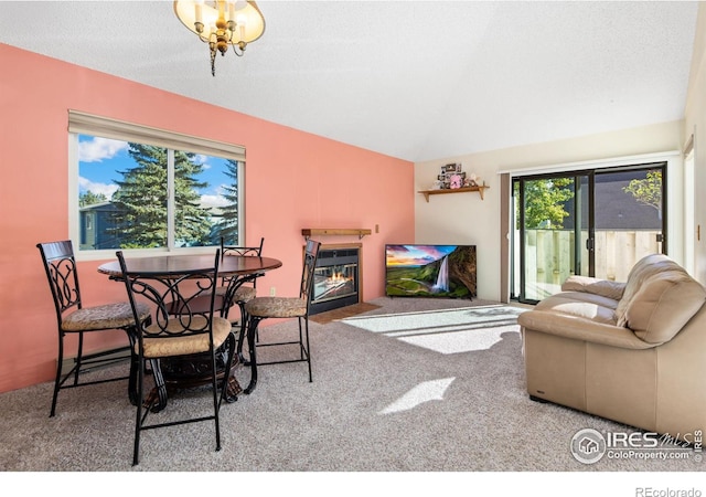 living room with carpet flooring, vaulted ceiling, a fireplace with flush hearth, and a textured ceiling