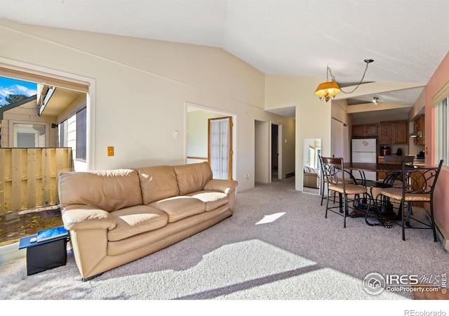 carpeted living room with a chandelier and vaulted ceiling