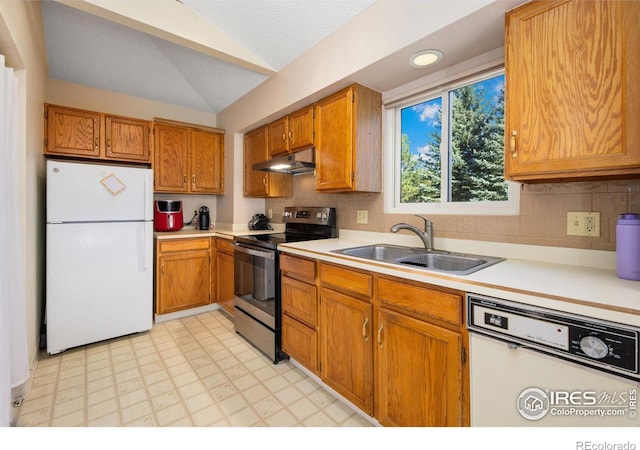 kitchen featuring white appliances, a sink, light countertops, vaulted ceiling, and under cabinet range hood