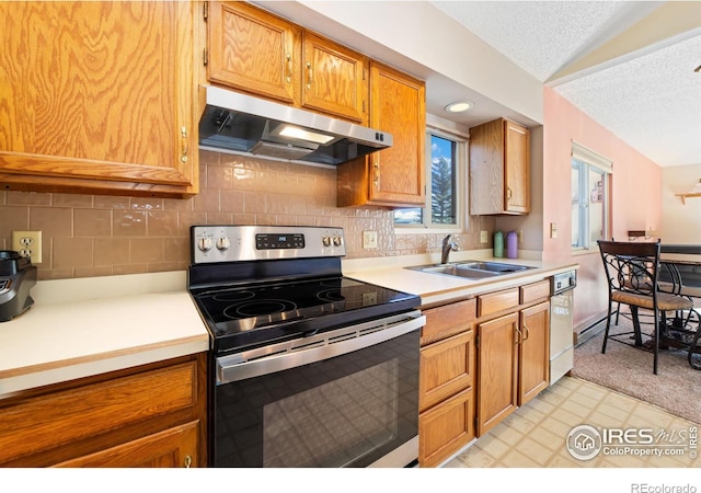 kitchen with a sink, light countertops, exhaust hood, and stainless steel range with electric cooktop