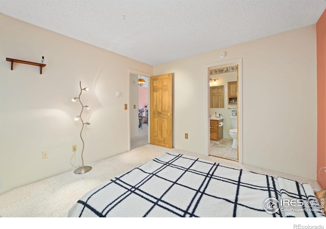 bedroom featuring light carpet, ensuite bathroom, and a textured ceiling