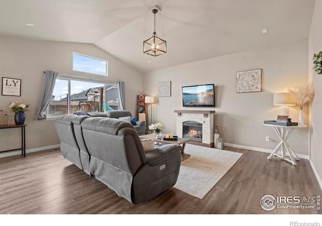 living area with baseboards, lofted ceiling, wood finished floors, and a fireplace