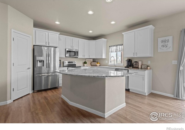 kitchen featuring light stone counters, white cabinets, and stainless steel appliances