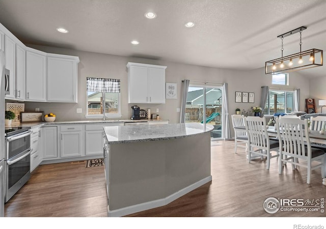 kitchen featuring white cabinetry, wood finished floors, double oven range, and a kitchen island