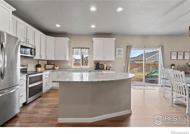 kitchen featuring white cabinetry, a center island, wood finished floors, and stainless steel appliances