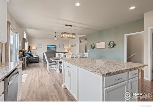 kitchen featuring stainless steel dishwasher, open floor plan, white cabinetry, light wood finished floors, and light stone countertops