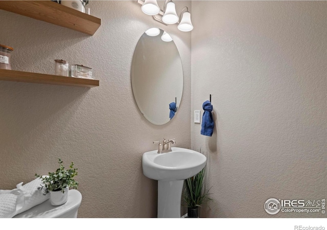 half bath with a notable chandelier and a textured wall