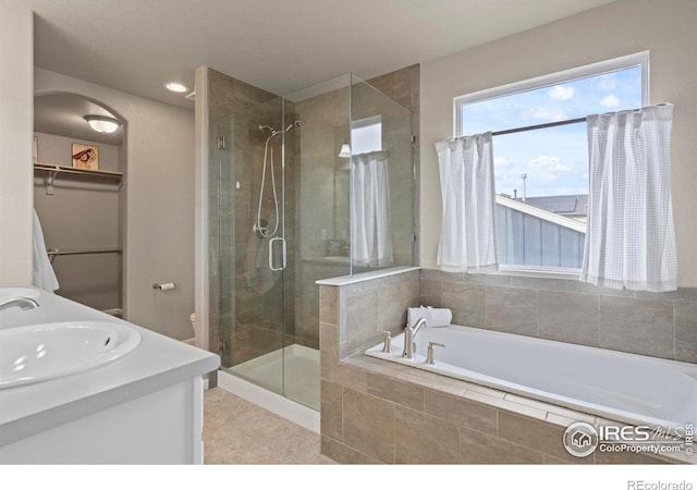 full bath featuring a stall shower, a sink, double vanity, a bath, and a spacious closet