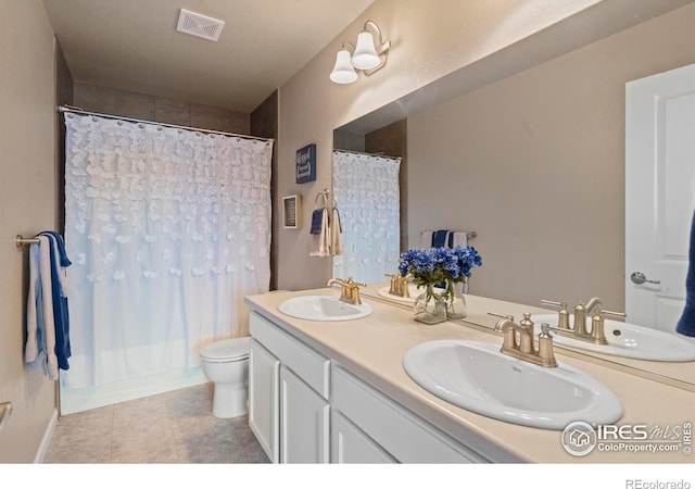 bathroom featuring double vanity, toilet, and a sink