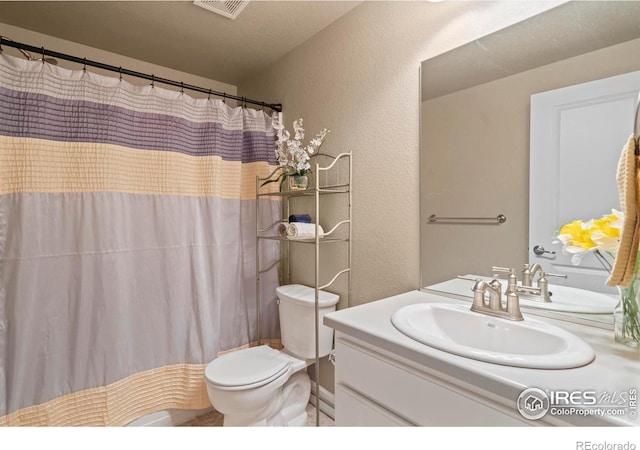 full bathroom featuring vanity, a shower with curtain, visible vents, toilet, and a textured wall