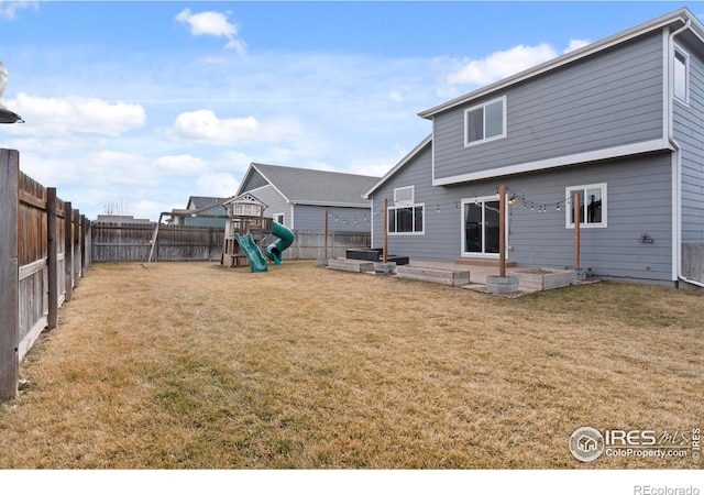 back of property featuring a patio area, a lawn, a fenced backyard, and a playground