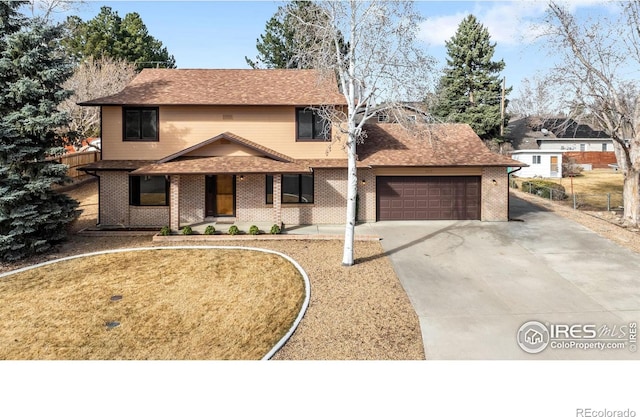 traditional-style home featuring driveway, fence, an attached garage, a shingled roof, and brick siding