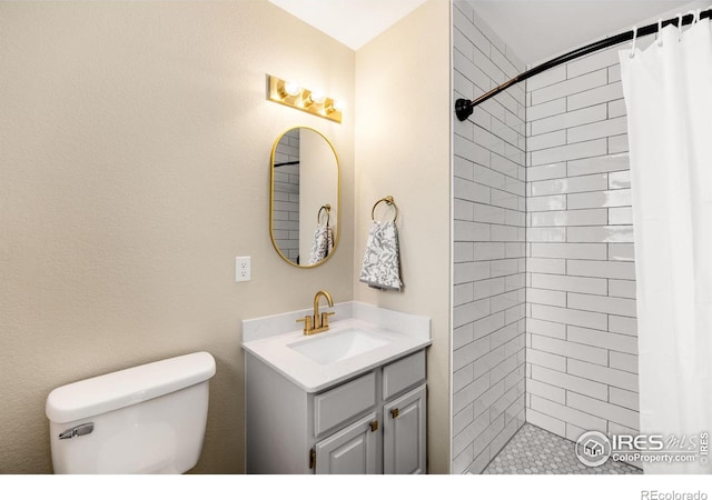 bathroom with tiled shower, toilet, and vanity