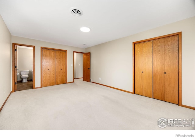 unfurnished bedroom with visible vents, light carpet, two closets, connected bathroom, and baseboards