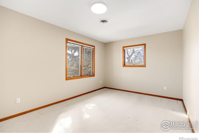 empty room featuring visible vents, carpet flooring, and baseboards