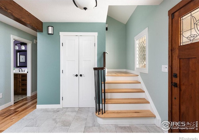 foyer featuring baseboards, wood finished floors, and stairs