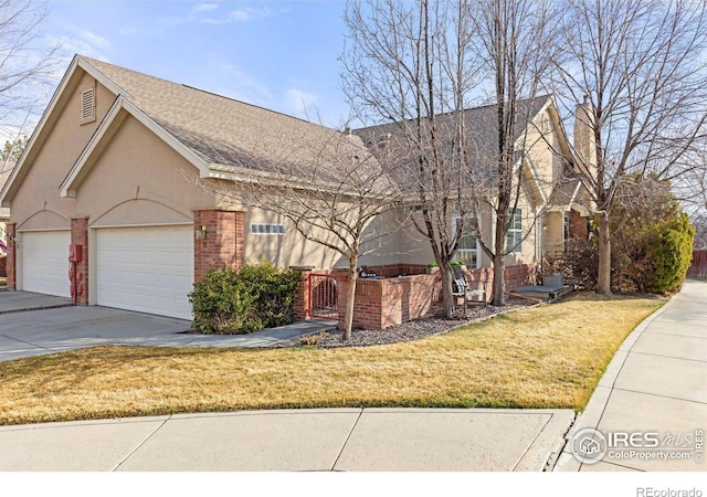 view of front of home featuring brick siding, a shingled roof, a front lawn, concrete driveway, and stucco siding