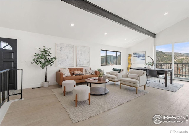 living area featuring baseboards, light wood-style flooring, recessed lighting, beamed ceiling, and a mountain view