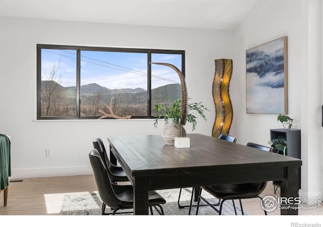 dining space with a mountain view, baseboards, and wood finished floors