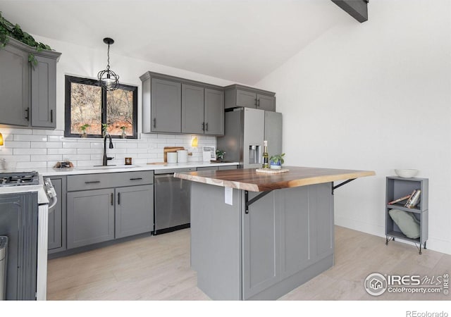 kitchen with a sink, stainless steel appliances, vaulted ceiling with beams, and gray cabinets