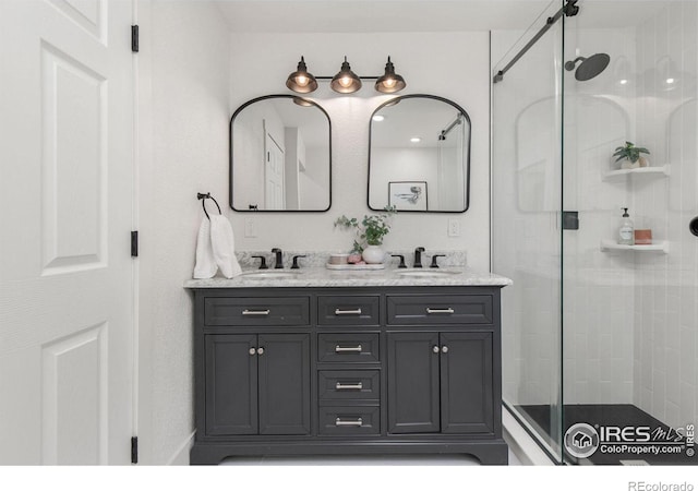 bathroom featuring double vanity, a stall shower, and a sink