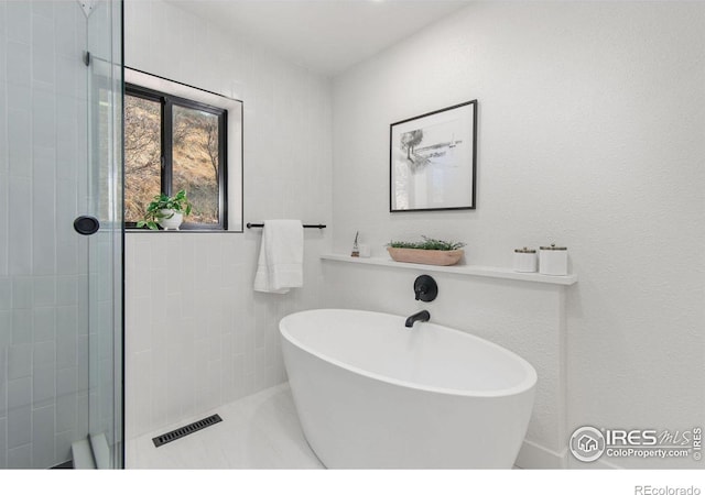 full bathroom with a soaking tub, visible vents, and a tile shower