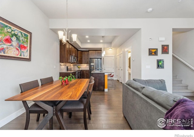 dining space featuring baseboards, a chandelier, stairs, hardwood / wood-style floors, and a raised ceiling