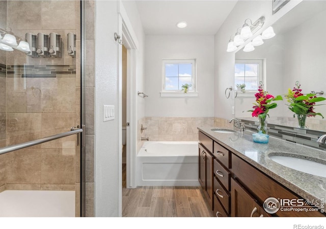 full bathroom featuring a stall shower, wood finished floors, a garden tub, and a sink