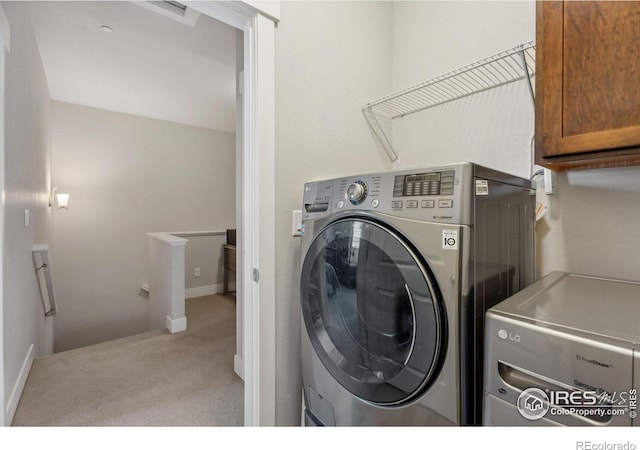 clothes washing area featuring baseboards, cabinet space, carpet, and washing machine and clothes dryer