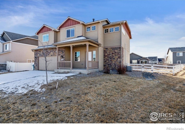 view of front of home featuring stone siding, covered porch, board and batten siding, and fence