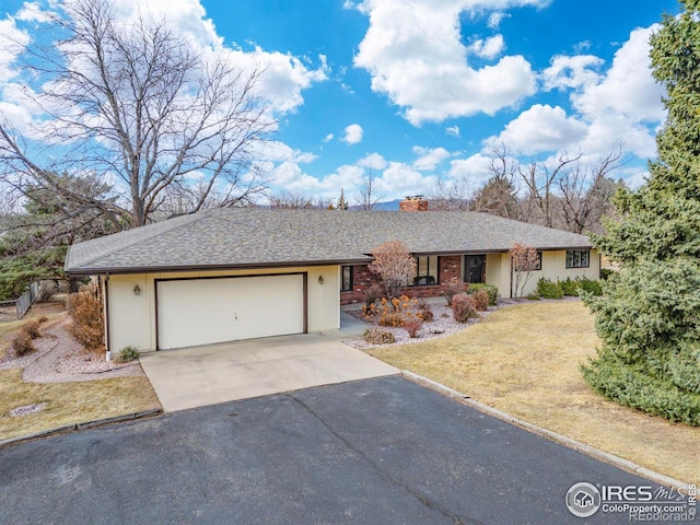 ranch-style house with driveway, roof with shingles, a front yard, a garage, and a chimney