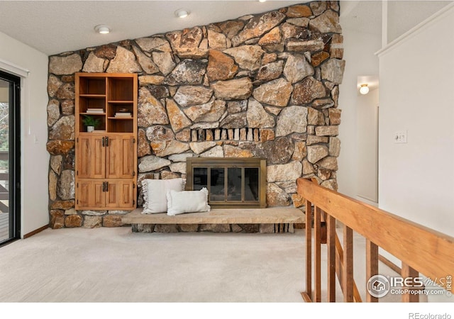 unfurnished living room featuring a stone fireplace, carpet flooring, and a textured ceiling