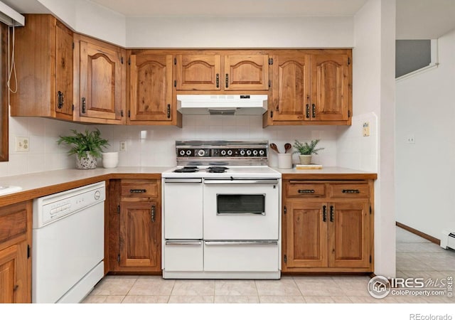 kitchen featuring white appliances, decorative backsplash, light countertops, under cabinet range hood, and brown cabinets