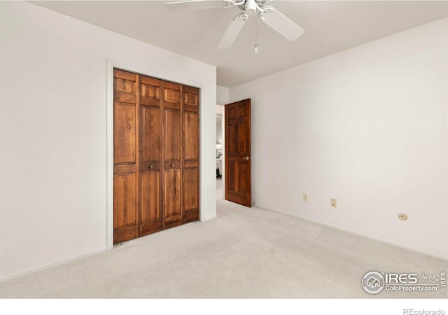 unfurnished bedroom featuring a closet, baseboards, light colored carpet, and a ceiling fan