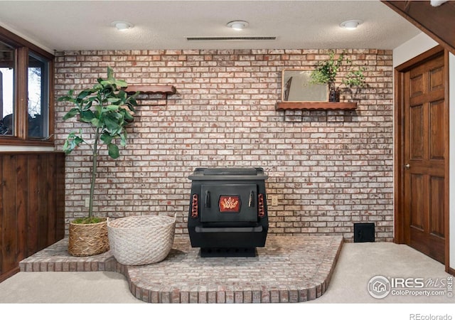 room details featuring visible vents, a textured ceiling, a wood stove, and carpet